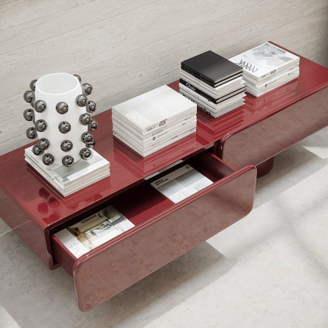 Glossy red console table with minimalist design, featuring white and black accents and a geometric vase.