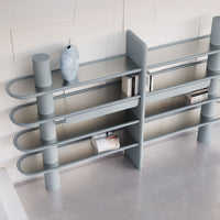 Modern light blue bookshelf with sleek curved lines and minimalist design, featuring a smooth finish and geometric patterns.