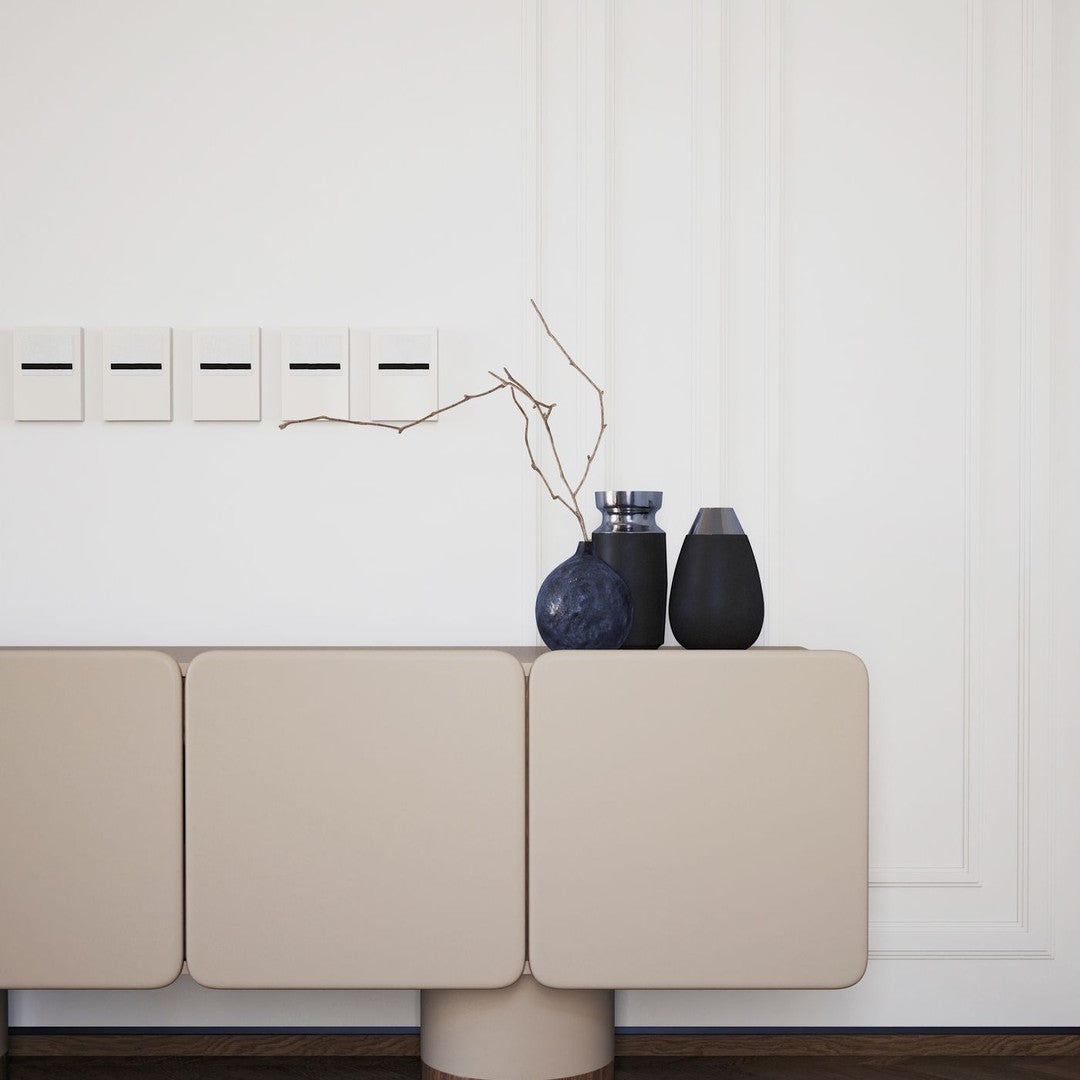 Beige modern cabinet with minimalistic design, accented by dark vases and a simple, elegant branch.