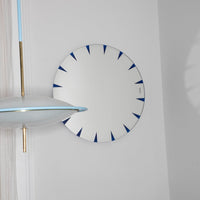 White circular mirror with blue accents and geometric spike pattern, ideal for modern decor.