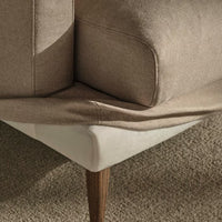 Tan and cream fabric corner of a sofa with smooth texture and natural wood legs, perfect for modern decor.