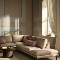 Beige sectional sofa with plum accent pillows against a softly patterned wall, complemented by light, airy curtains.