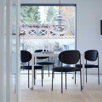 Modern dining set featuring sleek black chairs and a minimalist white table, set against a light wood floor and bright backdrop.