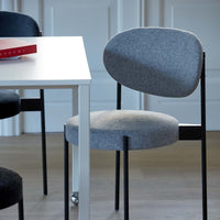 Gray upholstered chair with a sleek black frame, set beside a minimalist white table.