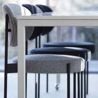 "Set of four stylish chairs featuring gray and black upholstery with sleek black legs against a modern table."