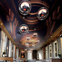 Elegant ceiling design with dark wood patterns, gold accents, and modern glass pendant lights. Sophisticated ambiance.