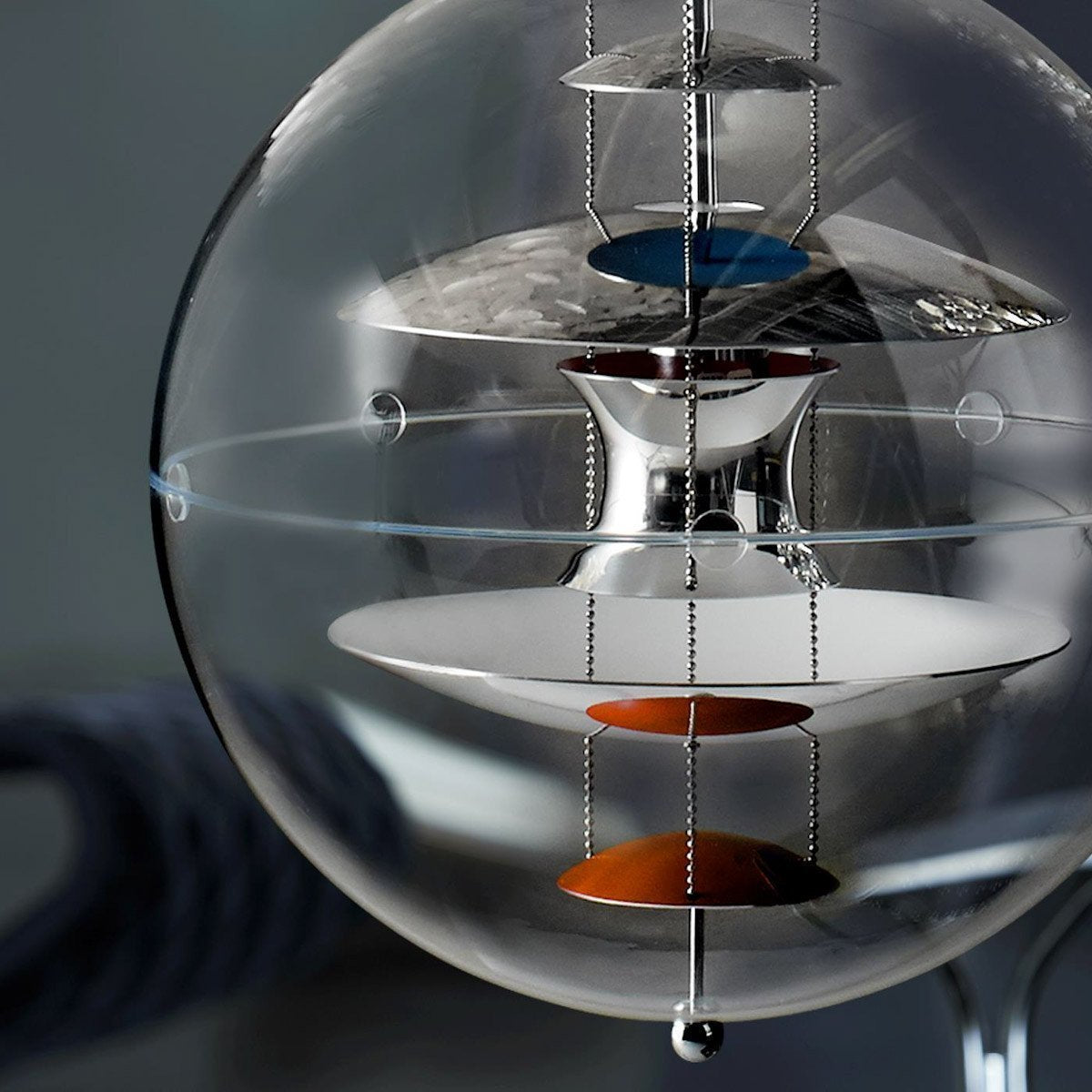 Clear glass orb with layered metallic discs in blue, white, and orange, featuring sleek, modern design elements.