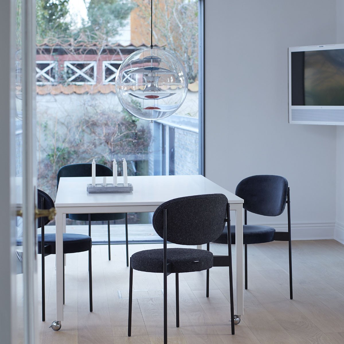 Modern dining setup with a white table and black chairs against a neutral backdrop. Elegant, minimalist aesthetic.