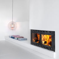 Modern fireplace with sleek black frame, surrounded by white walls; colorful striped and solid pattern books on the shelf.