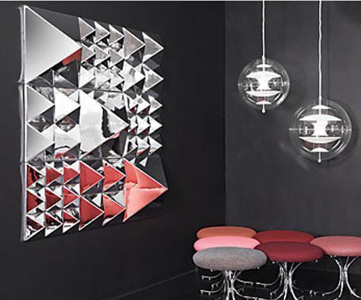 Sleek silver and red geometric wall art with triangular patterns, against a matte black background and modern seating.