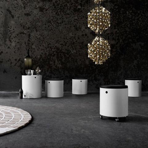 White modern storage stools with black tops, set against a textured dark wall and a light circular rug. Elegant atmosphere.