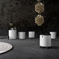 White modern storage stools with black tops, set against a textured dark wall and a light circular rug. Elegant atmosphere.