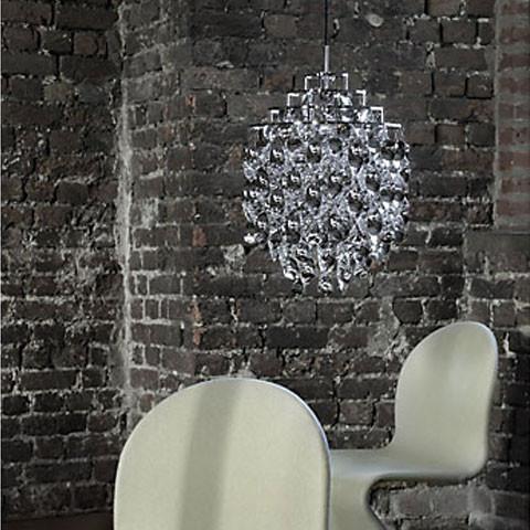 "Shimmering silver chandelier against textured dark brick wall; sleek white chair with subtle curves."