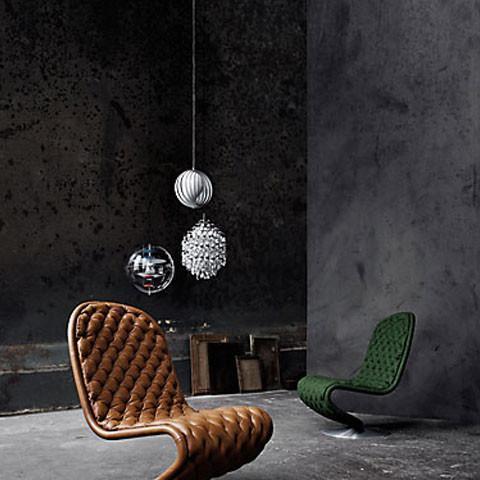 Modern chairs in brown and green textures, complemented by striking white and silver lighting against a dark gray background.