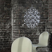 Sleek silver chandelier against a rustic dark brick wall, featuring smooth, modern curves in a soft neutral chair.