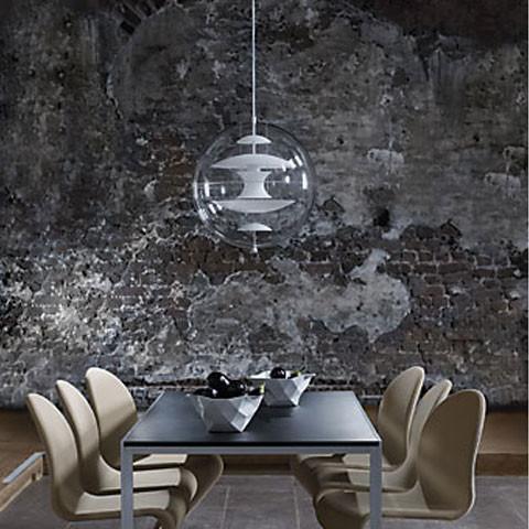 Clear globe pendant light above a dark wood dining table with beige chairs, against a textured gray wall.