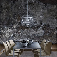 Clear globe pendant light above a dark wood dining table with beige chairs, against a textured gray wall.