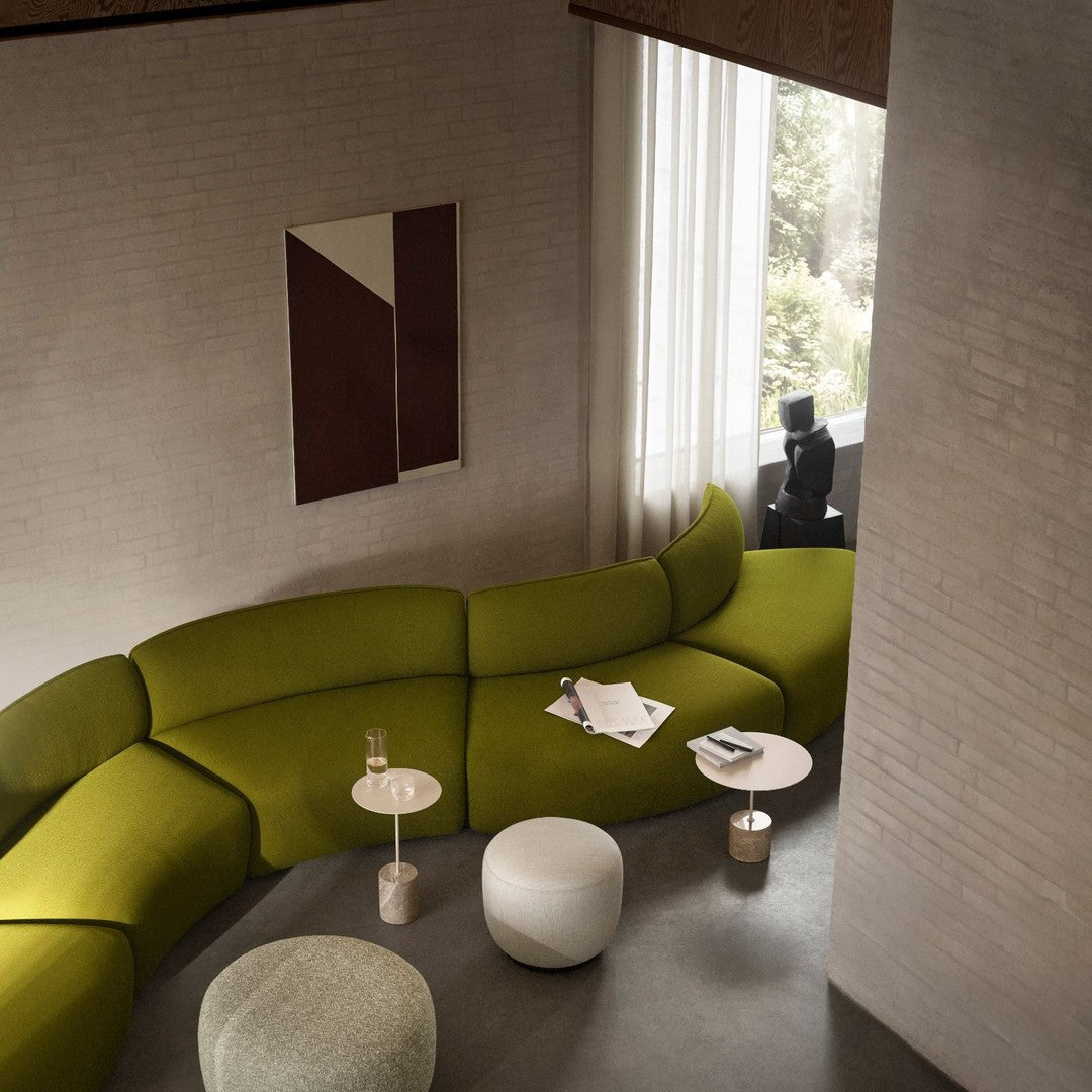 "Curved green sofa with subtle texture, paired with minimalist white and beige furniture, set in a modern interior."