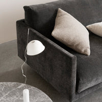 "Dark gray upholstered sofa with light beige accent pillows, alongside a marble coffee table and modern white lamp."