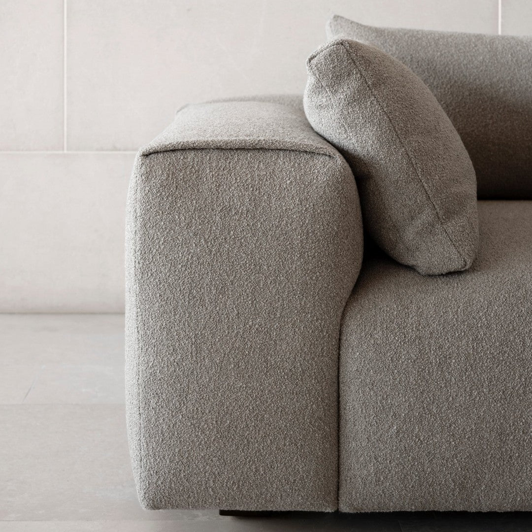 Light gray textured sofa with a smooth finish and rounded cushion, featuring a minimalist and modern design.