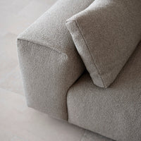 Close-up of a light beige, textured fabric sofa with a soft, inviting surface and minimalistic design.