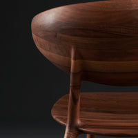 "Close-up of a rich walnut chair with smooth, rounded edges and elegant wood grains."