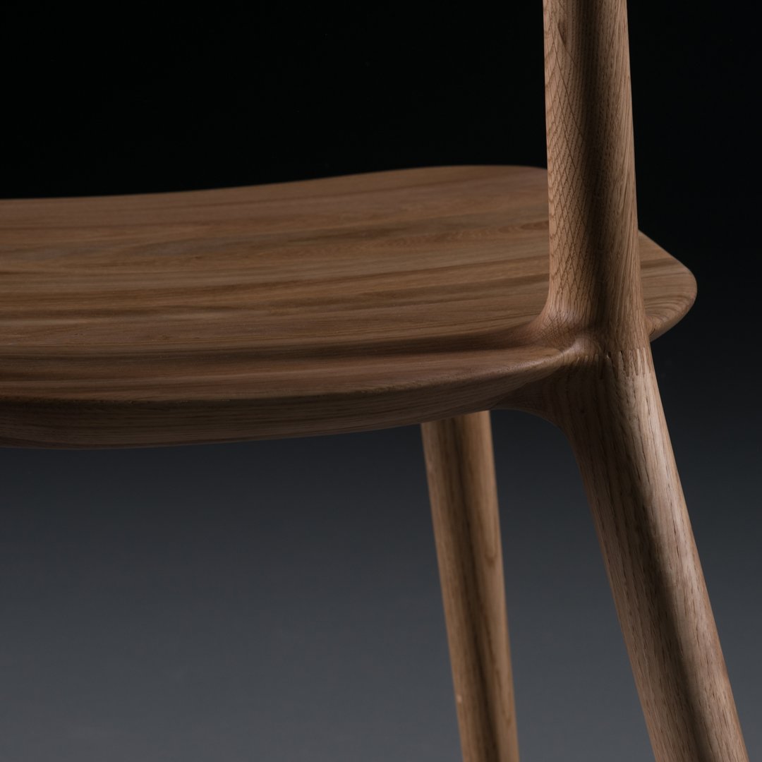 Wooden chair with a smooth, warm walnut finish and minimalist design, showcasing natural grain patterns.