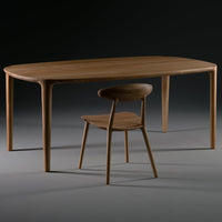 Natural wood dining table with a smooth finish and a contemporary curved design, paired with a minimalist wooden chair.