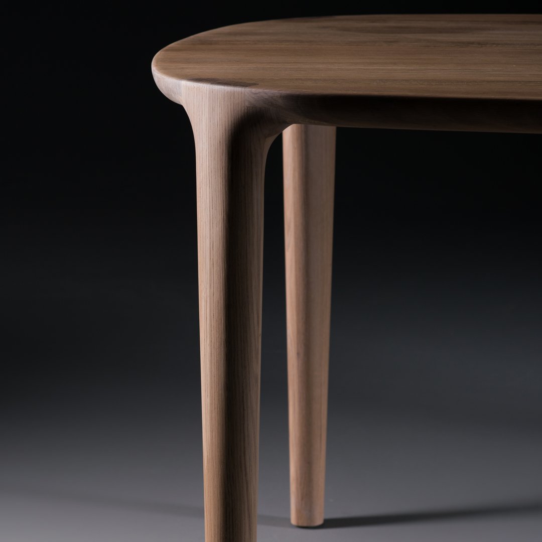 Smooth walnut wood table leg with rounded edges and a stylish, minimal design against a dark background.