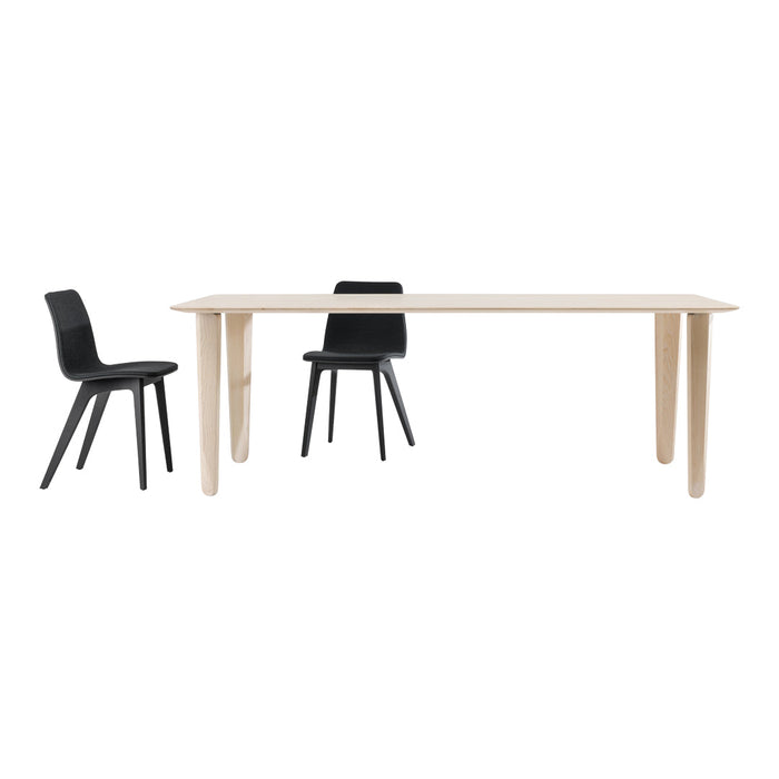 Modern light wood dining table with sleek black chairs, featuring minimalist design and smooth finishes.