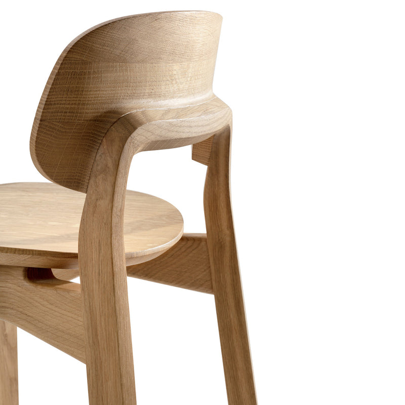 Light oak wooden chair showcasing a smooth, curved backrest and clean lines; minimalistic design with a natural finish.