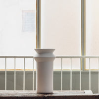 White ceramic vase with a smooth texture and minimalist design, featuring subtle curves and a modern silhouette.